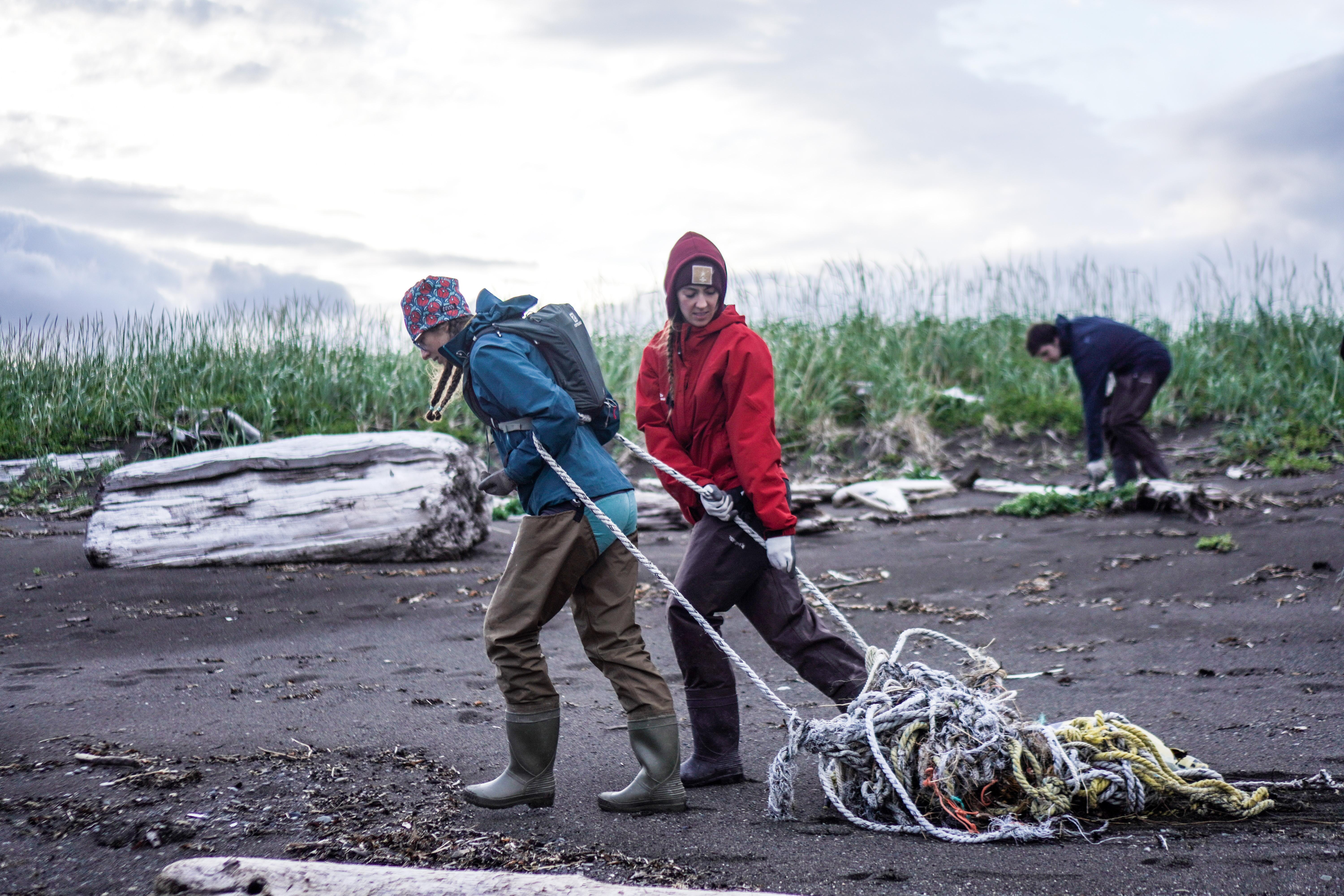 Scientists drag debris along a beach.