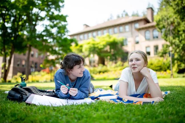 两个学生在Old Main前的草坪上休息.
